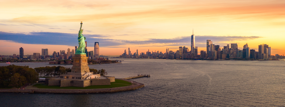 Liberty statue in New York city with manhatttan background and sunset, New York, USA