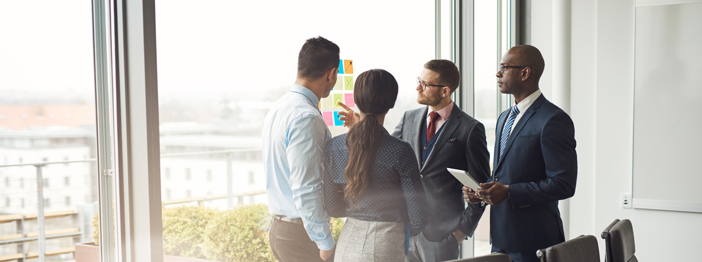 Diverse,Multiracial,Management,Team,Standing,Grouped,In,Front,Of,A